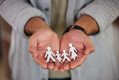 Woman holding in her hands cut out figures of a family of four